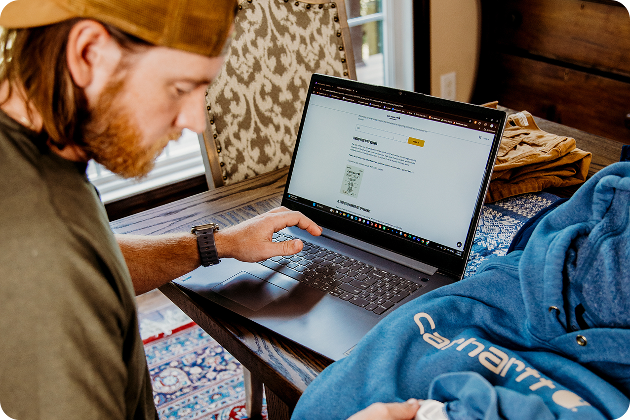 A person using a laptop at home to prepare a Carhartt Reworked trade-in