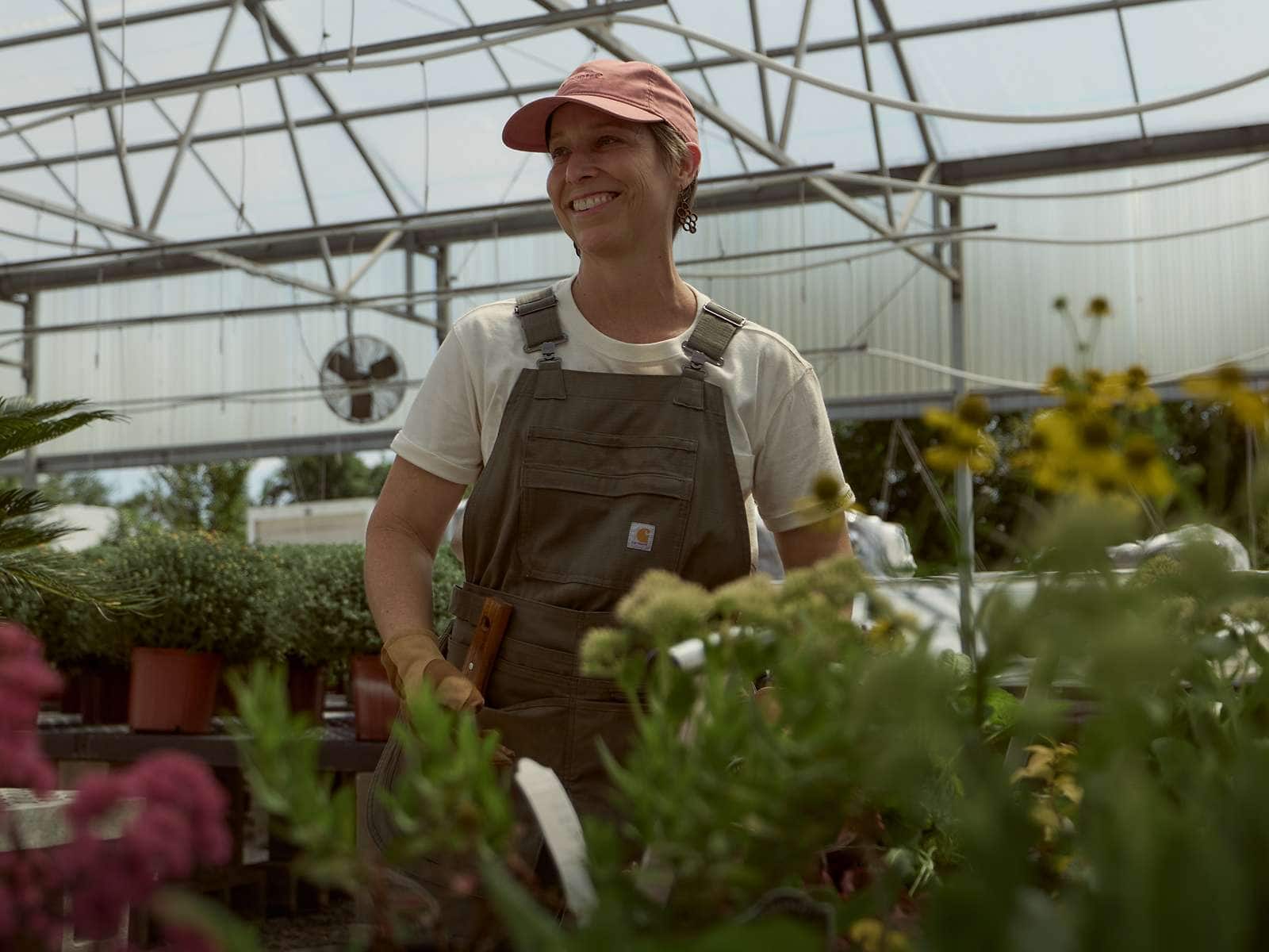 Fran from Ozark Green Roofs working in a greenhouse while wearing Carhartt gardening gear.