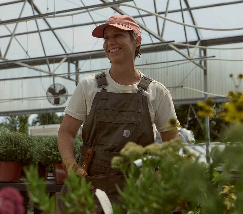 Fran from Ozark Green Roofs working in a greenhouse while wearing Carhartt gardening gear.