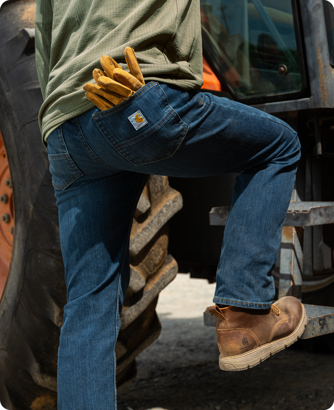Person stepping up onto equipment in Carhartt men's relaxed fit work pants that offer extra room through the seat and thigh