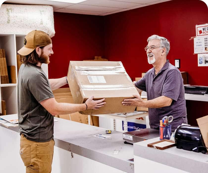 Nick handing the box contaning his used gear to an employee at a shipping store.